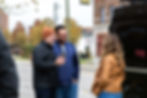 Paul Domish with two clients laughing during a FaceTime call in front of their new custom Drifter Vans Ford Transit build