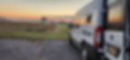Susan’s Drifter Van parked against the backdrop of a stunning sunrise, with warm light illuminating the van and casting soft glows across the landscape.